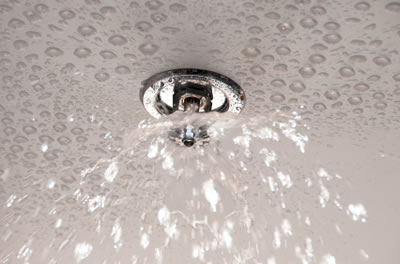 Fire sprinkler going off on a white ceiling.