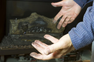 Man's hands covered in soot in front of dirty gas fireplace