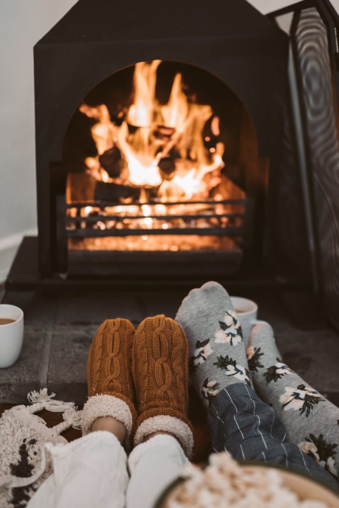 Socked feet propped in front of fireplace.
